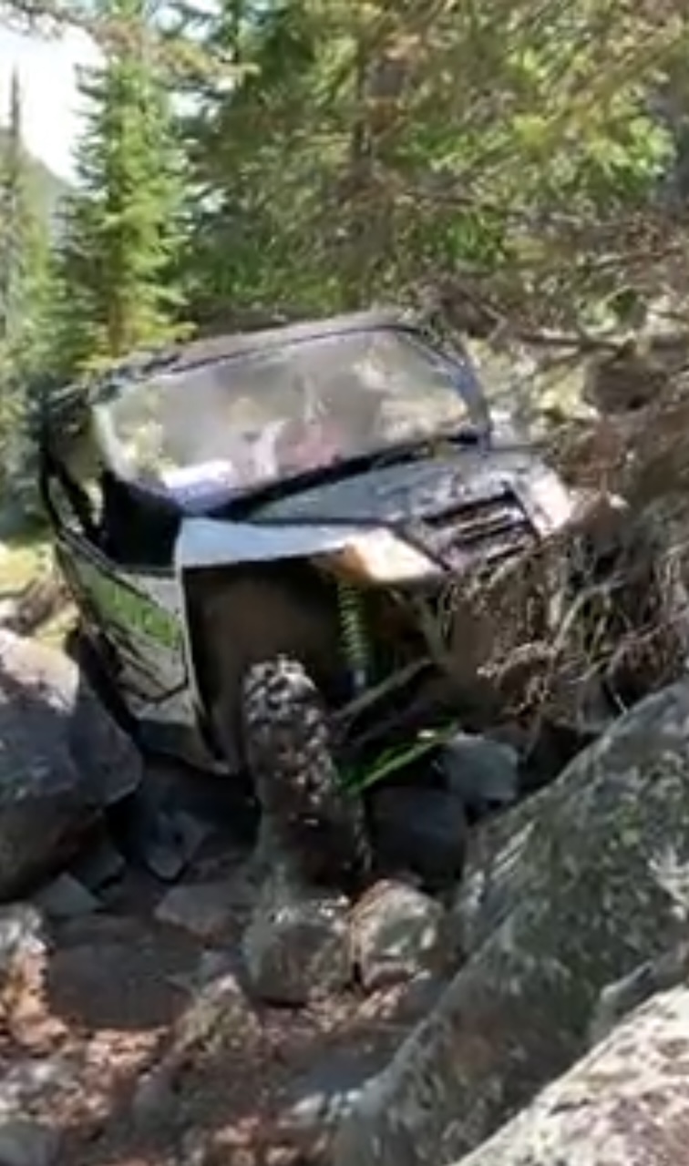 UTV navigating rocky boulder terrain in Montana mountain forest