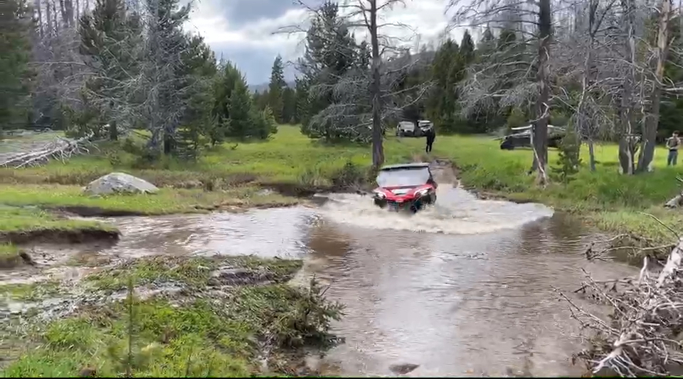 Off-road vehicles on muddy forest trail in Montana backcountry terrain